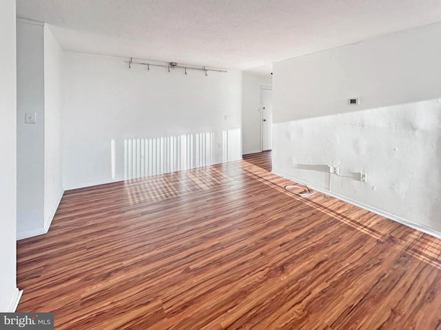 spare room with a textured ceiling and wood finished floors