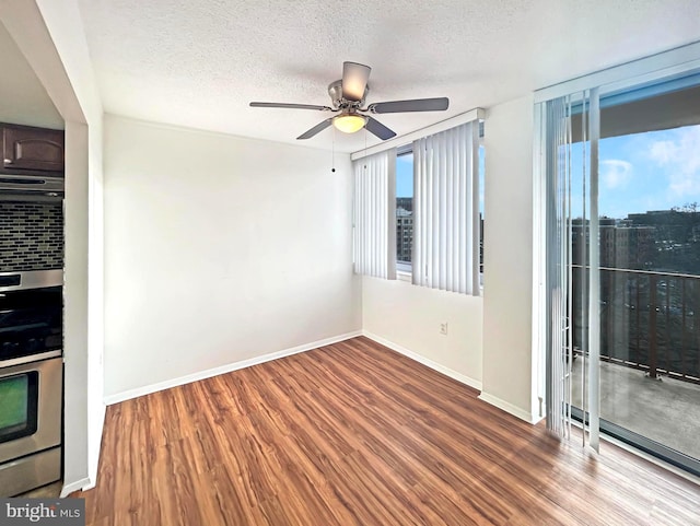 spare room with ceiling fan, a textured ceiling, baseboards, and wood finished floors