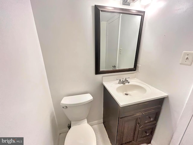 half bathroom with vanity, toilet, and baseboards