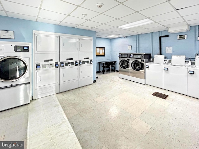 shared laundry area with concrete block wall, washing machine and clothes dryer, and stacked washing maching and dryer