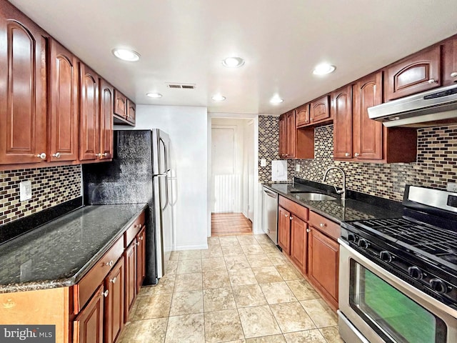 kitchen with visible vents, dark stone counters, appliances with stainless steel finishes, under cabinet range hood, and a sink