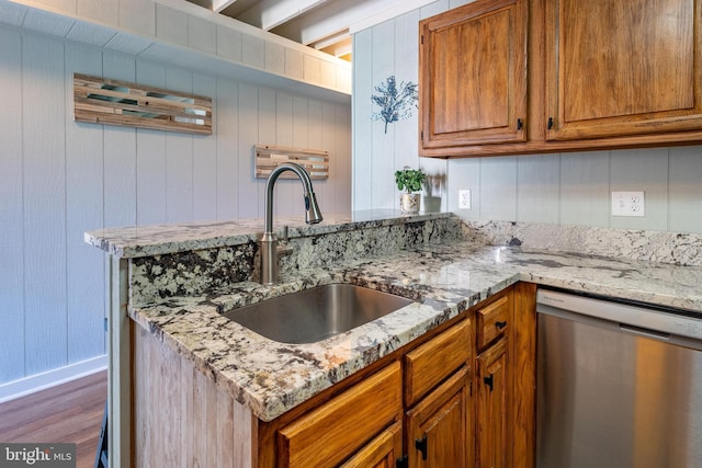 kitchen featuring light stone countertops, sink, stainless steel dishwasher, and dark wood-type flooring