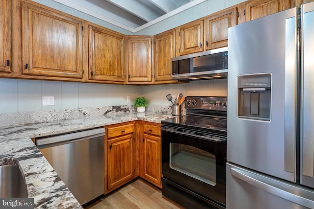 kitchen featuring appliances with stainless steel finishes, light stone counters, and light hardwood / wood-style floors