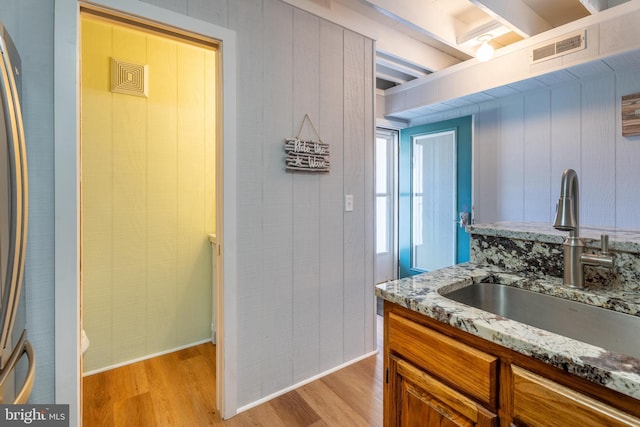 kitchen featuring sink, light hardwood / wood-style flooring, and stone countertops