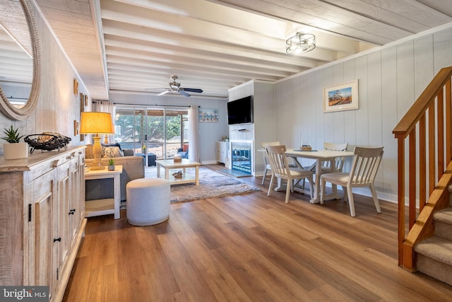 living room featuring hardwood / wood-style flooring, ceiling fan, and beamed ceiling