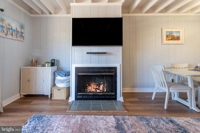 living room with beamed ceiling, a tiled fireplace, and dark hardwood / wood-style flooring