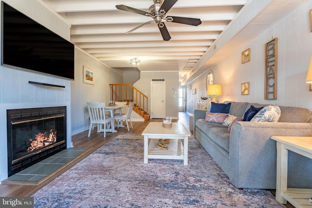 living room featuring beamed ceiling, a tiled fireplace, ceiling fan, and dark hardwood / wood-style flooring