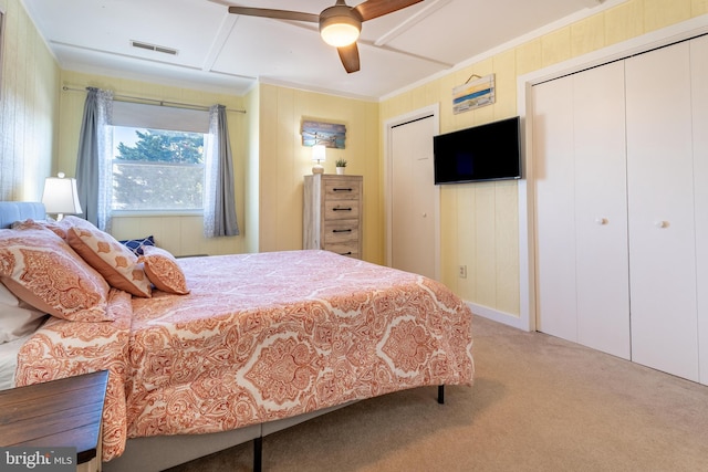 carpeted bedroom featuring crown molding, ceiling fan, and two closets