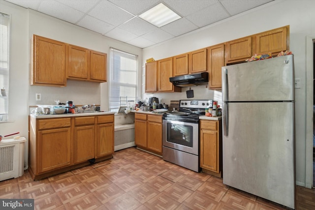 kitchen featuring a drop ceiling, radiator heating unit, stainless steel appliances, and light parquet flooring