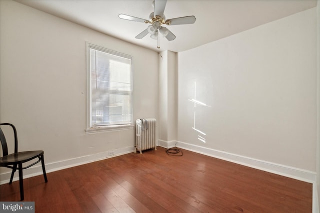 unfurnished room featuring dark wood-type flooring, ceiling fan, and radiator heating unit