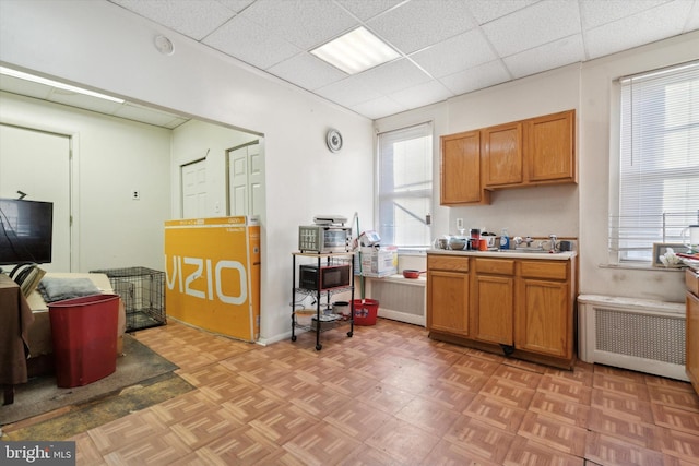 kitchen featuring a paneled ceiling, light parquet flooring, and radiator