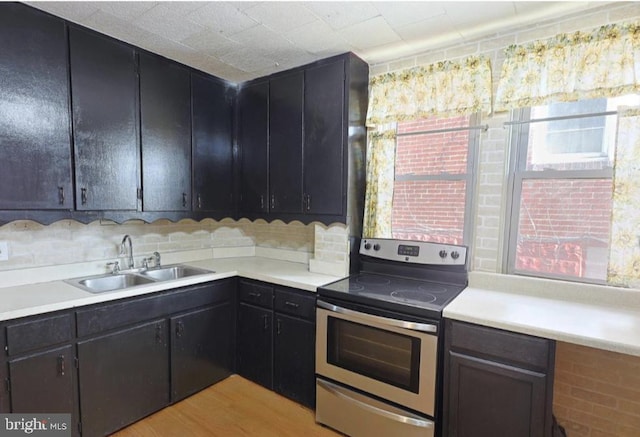 kitchen with sink, backsplash, stainless steel electric stove, and light wood-type flooring