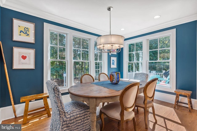 dining space with ornamental molding, hardwood / wood-style floors, and a chandelier