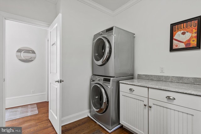 clothes washing area with dark hardwood / wood-style flooring, stacked washer / drying machine, crown molding, and cabinets