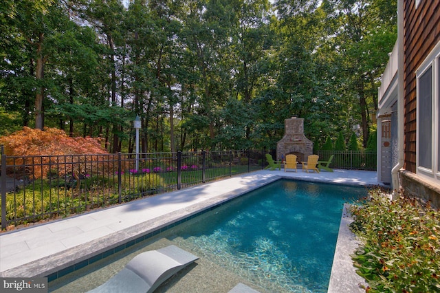 view of swimming pool featuring a patio area and an outdoor stone fireplace