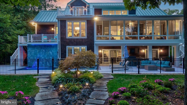 back house at dusk with a fenced in pool, a balcony, an outdoor hangout area, and a patio area