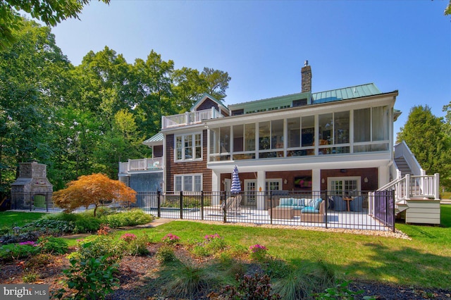 back of house featuring a sunroom, a fireplace, a fenced in pool, and a patio