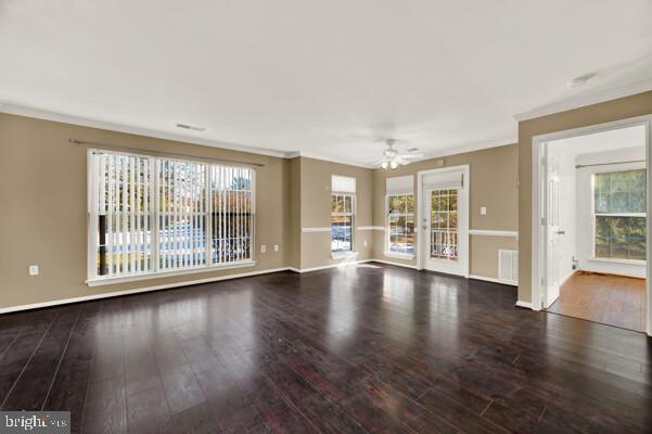 unfurnished living room featuring visible vents, ornamental molding, ceiling fan, wood finished floors, and baseboards