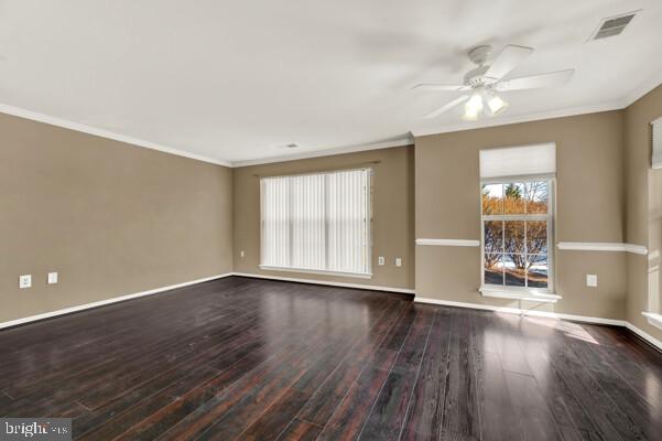 unfurnished room with baseboards, visible vents, wood finished floors, and ornamental molding