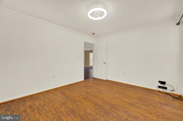 unfurnished room with baseboards, wood finished floors, and crown molding