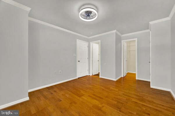 unfurnished bedroom with ornamental molding, wood finished floors, and baseboards