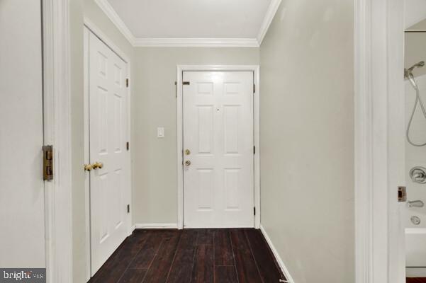 entryway featuring ornamental molding, dark wood-type flooring, and baseboards