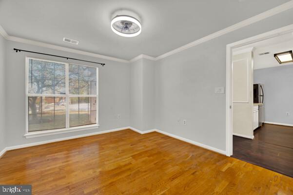 unfurnished room featuring visible vents, baseboards, dark wood-type flooring, and crown molding