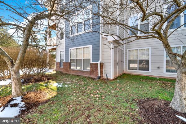 view of side of home featuring a yard, a chimney, and brick siding