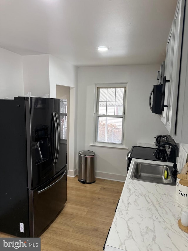 kitchen with black fridge, light hardwood / wood-style floors, and sink