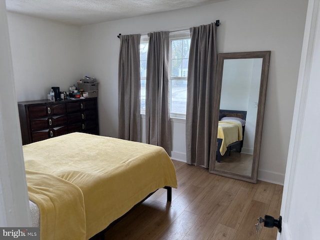 bedroom featuring light hardwood / wood-style flooring and a textured ceiling