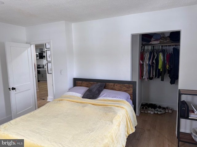 bedroom featuring wood-type flooring, a closet, and a textured ceiling