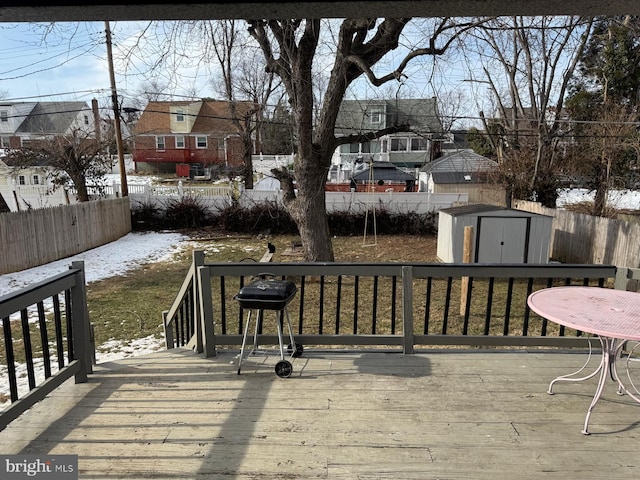 snow covered deck with a grill, a yard, and a shed