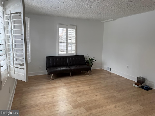 living area with light hardwood / wood-style flooring and a textured ceiling