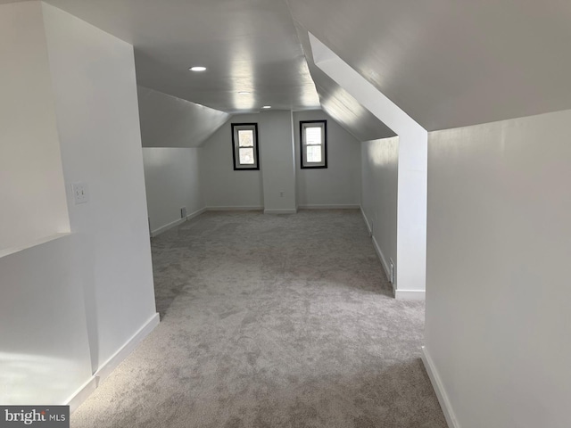 bonus room with lofted ceiling and light carpet