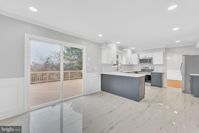 kitchen featuring stainless steel appliances, white cabinetry, crown molding, and kitchen peninsula