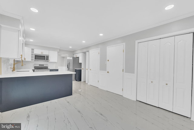 kitchen with sink, appliances with stainless steel finishes, white cabinetry, ornamental molding, and kitchen peninsula