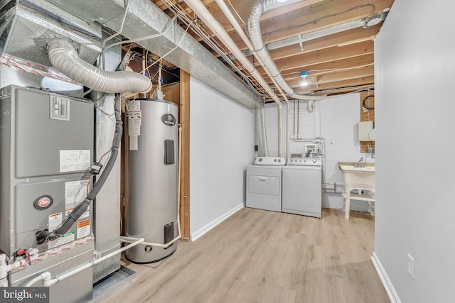 basement with sink, heating unit, light wood-type flooring, electric water heater, and washing machine and dryer