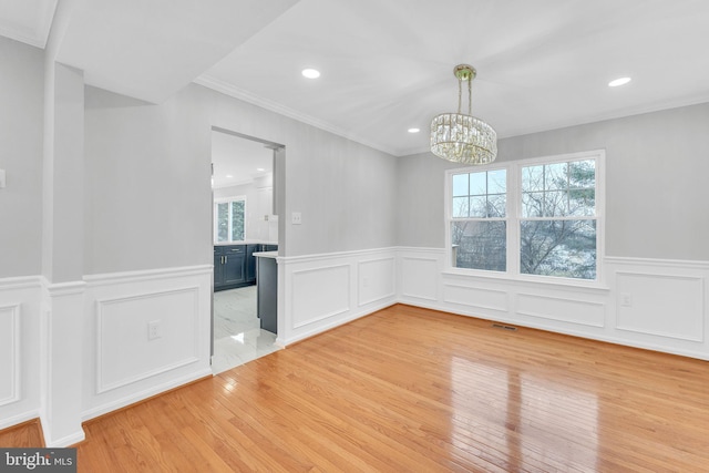 unfurnished room featuring crown molding, a chandelier, and light hardwood / wood-style floors