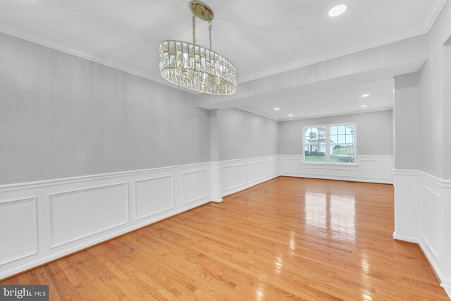 empty room with an inviting chandelier, crown molding, and light hardwood / wood-style flooring