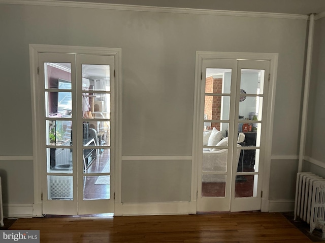 doorway with dark hardwood / wood-style flooring, crown molding, radiator heating unit, and french doors