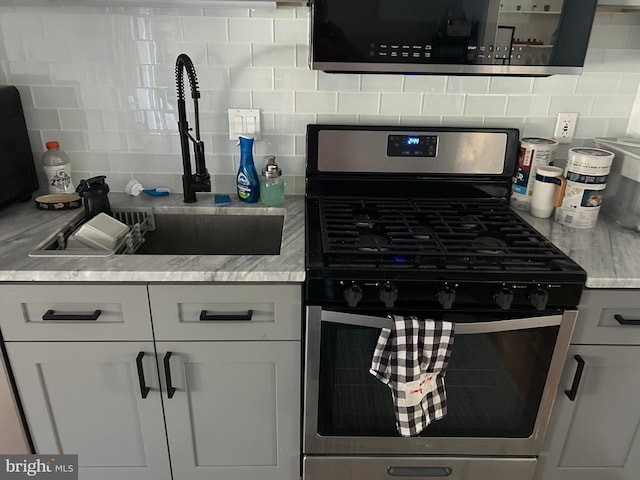 kitchen with white cabinetry, sink, gas stove, and backsplash