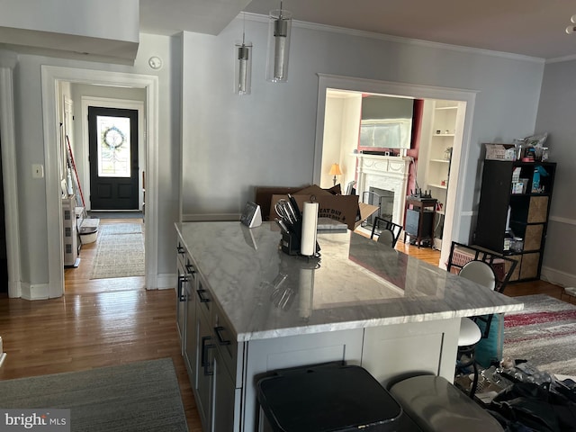 kitchen with pendant lighting, a breakfast bar area, gray cabinetry, light stone countertops, and light hardwood / wood-style floors