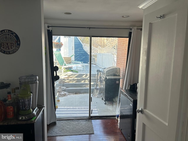 doorway to outside with ornamental molding and dark hardwood / wood-style floors