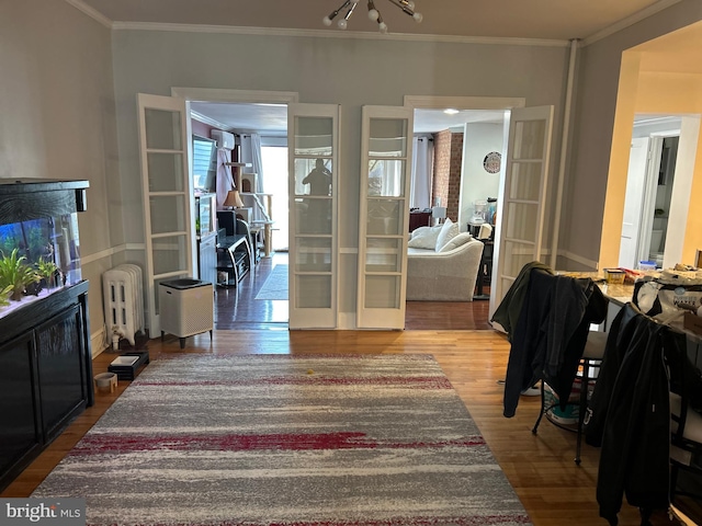 interior space featuring hardwood / wood-style flooring, radiator heating unit, crown molding, and french doors