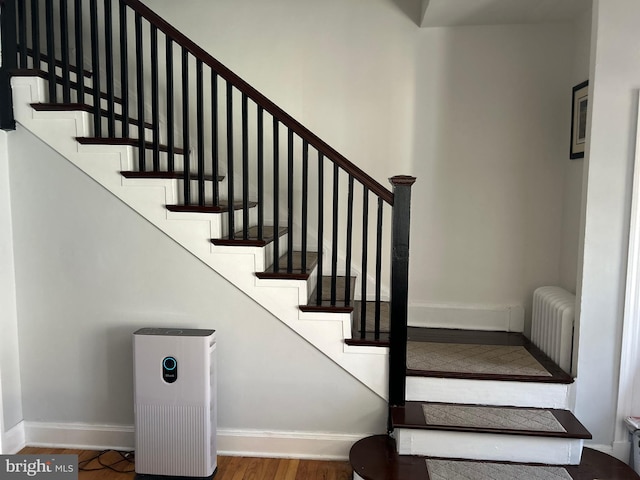 stairway featuring radiator heating unit and hardwood / wood-style floors