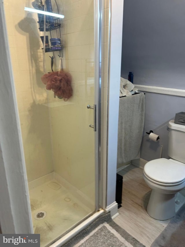 bathroom featuring toilet, an enclosed shower, and hardwood / wood-style floors