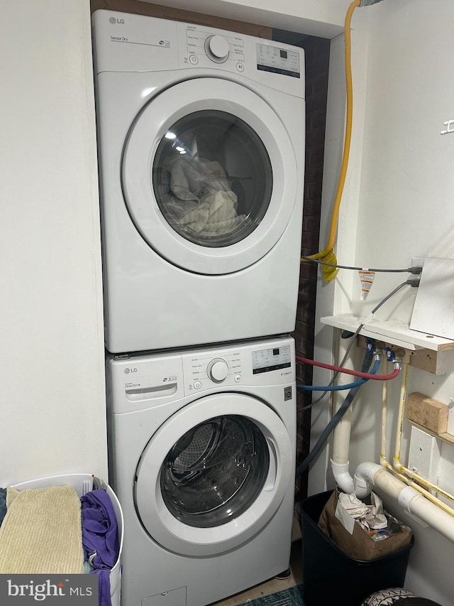 clothes washing area featuring stacked washer and dryer