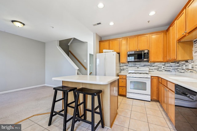 kitchen with a breakfast bar, sink, light carpet, a kitchen island, and white appliances