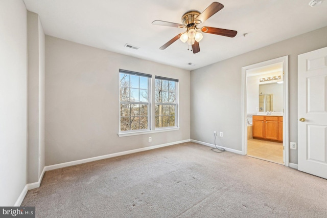 unfurnished bedroom featuring light carpet, connected bathroom, and ceiling fan