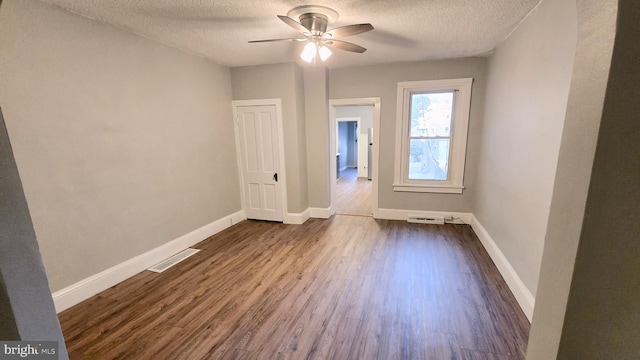 spare room featuring ceiling fan, dark wood-type flooring, and a textured ceiling